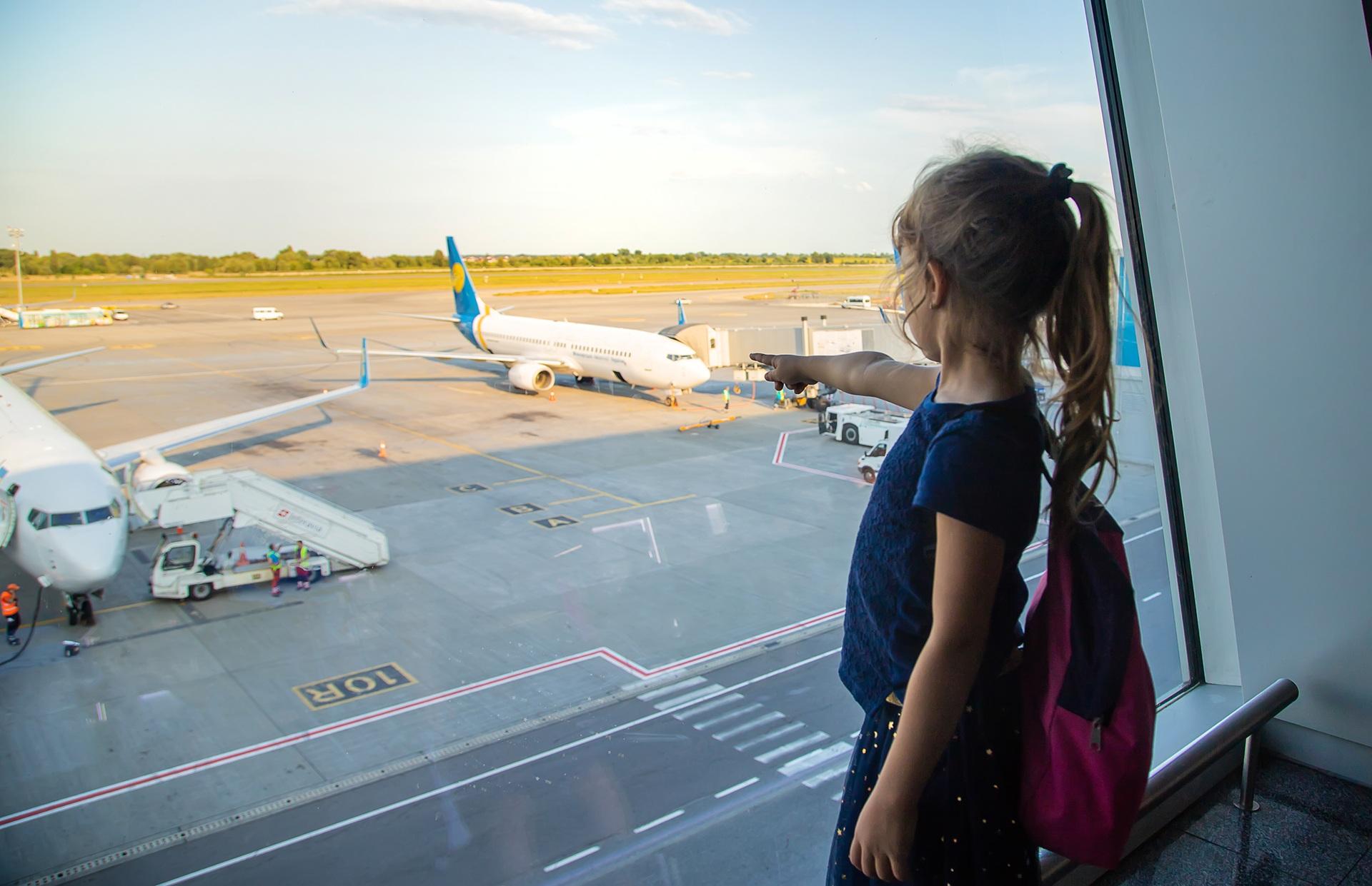 Mädchen zeigt auf Flugzeug am Gate | Lufthansa First Class


