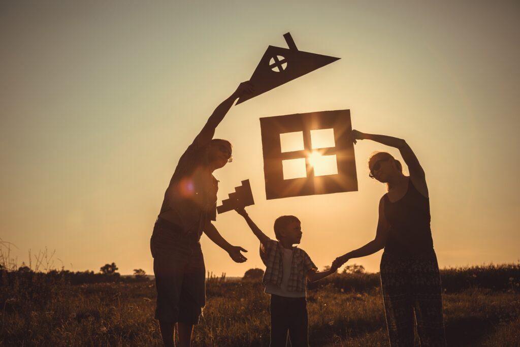 Familie hält symbolische Hausteile vor untergehender Sonne | Photovoltaik Halle